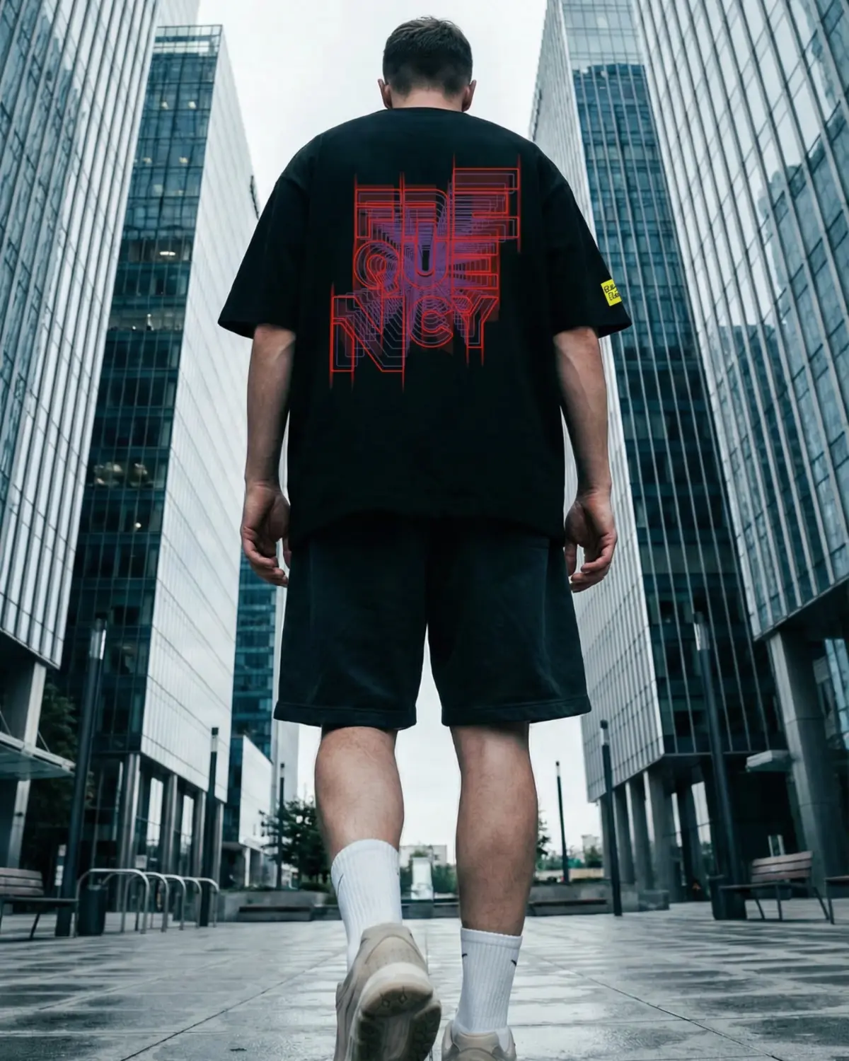 Backbeat Wear graphic tee worn by model walking between modern skyscrapers